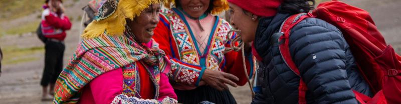 A traveler chatting and laughing with two local women in Cusco, Peru 