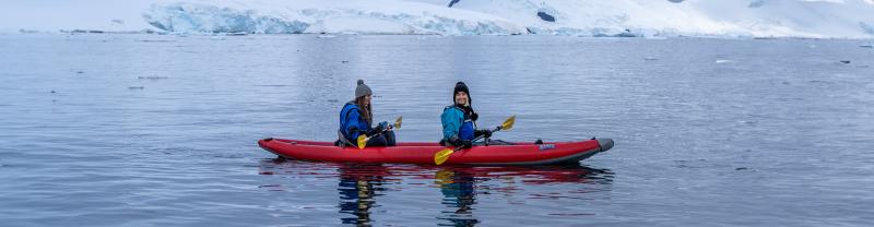 Two Ocean Endeavour passengers paddling an inflatable kayak in Antarctica