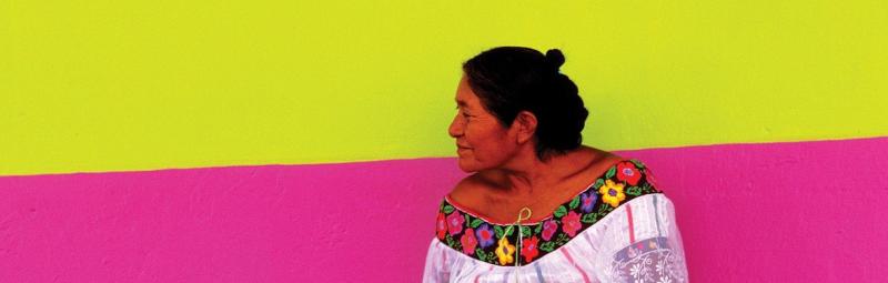 Mexican woman standing in front of a yellow and pink wall