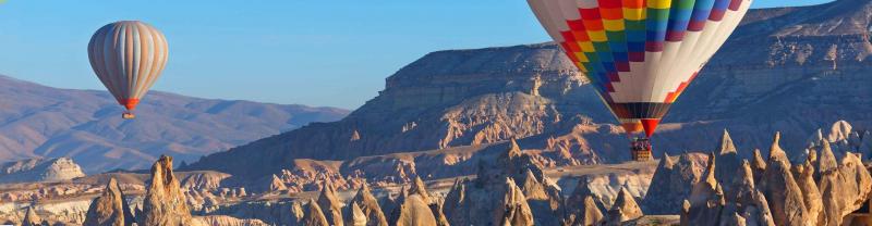 Two hot air balloons flying over the rugged landscape of Göreme in Cappadocia, Turkey
