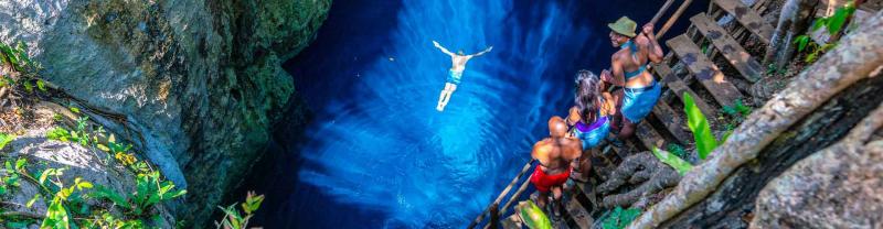 Traveler goes for a swim in blue waters of Cenote in Mexico
