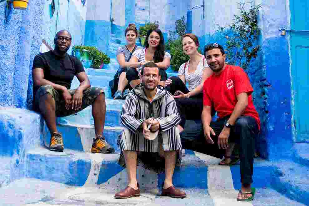 Intrepid group sit on the blue stairs of Chefchaouen