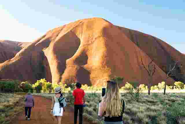 Three travellers and an Intrepid guide walking towards the base of Uluru