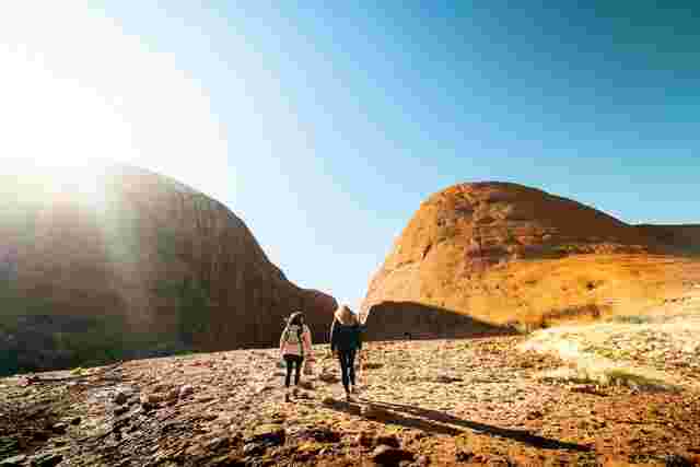 Two travellers walking through the domes of Kata Tjuta on the Walpa Gorge Walk