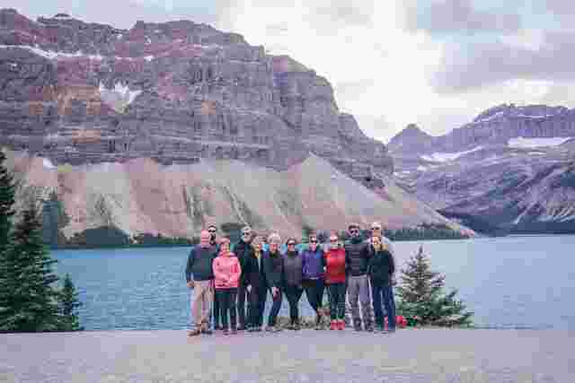 A group of travelers standing in front of a lake in the Canadian Rockies 