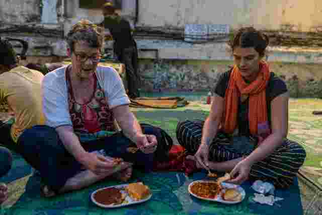 Two travellers sat on the floor eating a traditional meal in Goa, India