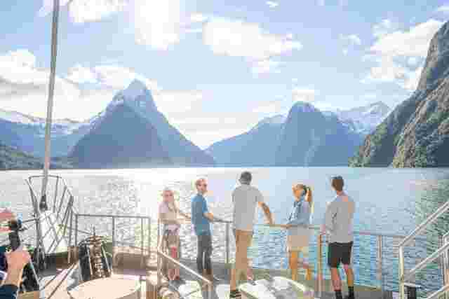 A group of people standing at the railing of a boat during a cruise of Milford Sound. 