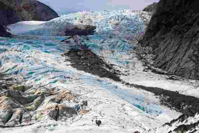 A group of hikers standing at the bottom of Franz Josef Glacier