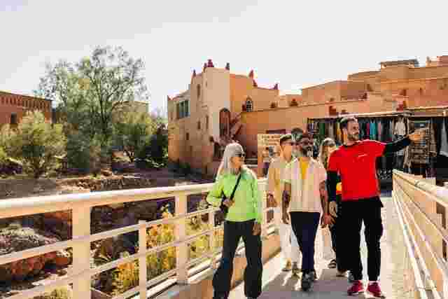 Four Intrepid travellers and a local leader walking over a bridge in Aït Benhaddou, Morocco