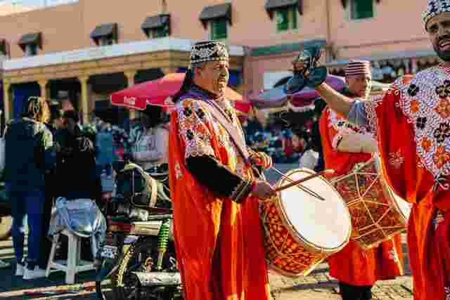 Two Moroccan men wearing traditional dress and playing the drums in Marrakesh