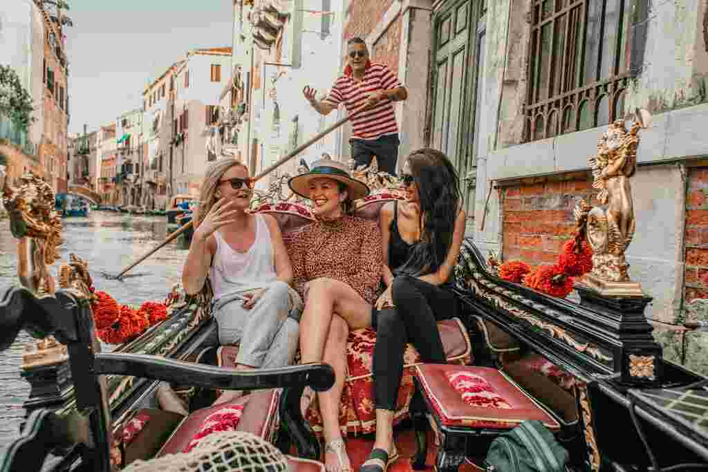 A group of friends laugh as they take a gondola ride in Italy.