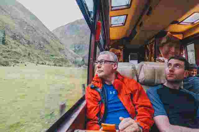 A couple of travellers looking out of a window on the train journey to Machu Picchu. 