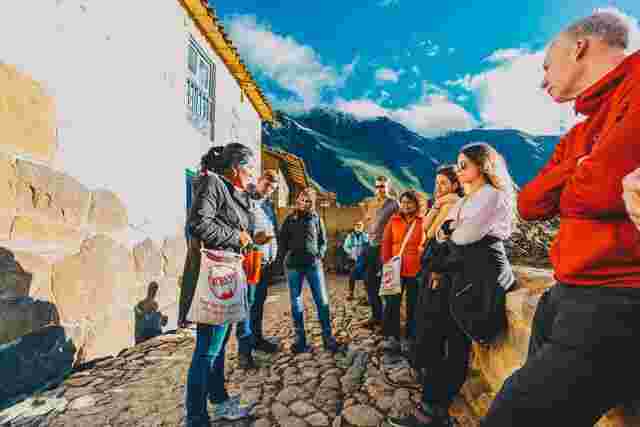 A group of people crowded around a local leader in the streets of Ollantaytambo