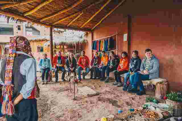 A group of travellers sitting with locals in the Sacred Valley in Peru
