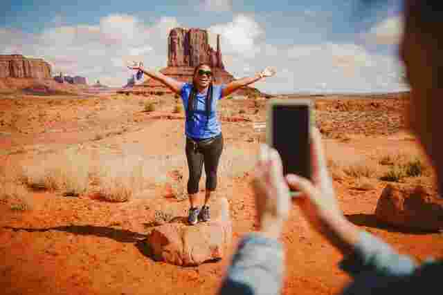 A woman posing for a photo in front of iconic rock formations in Monument Valley. 