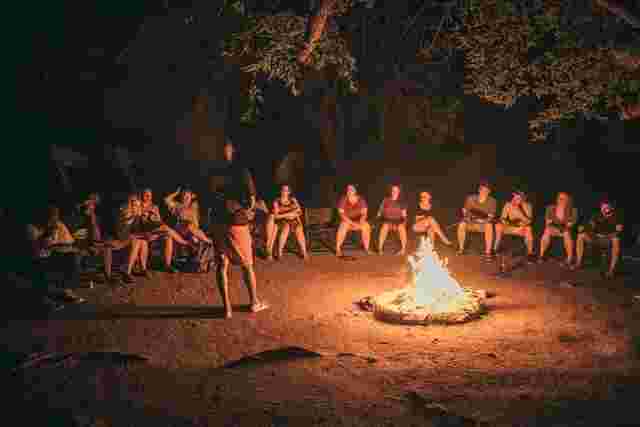 A group of travelers sat around a campfire in the Okavango Delta bush
