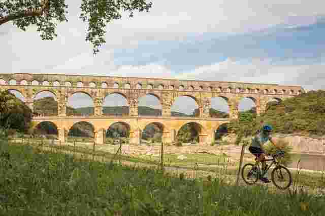 A cyclist riding past the Pont du Gard in France
