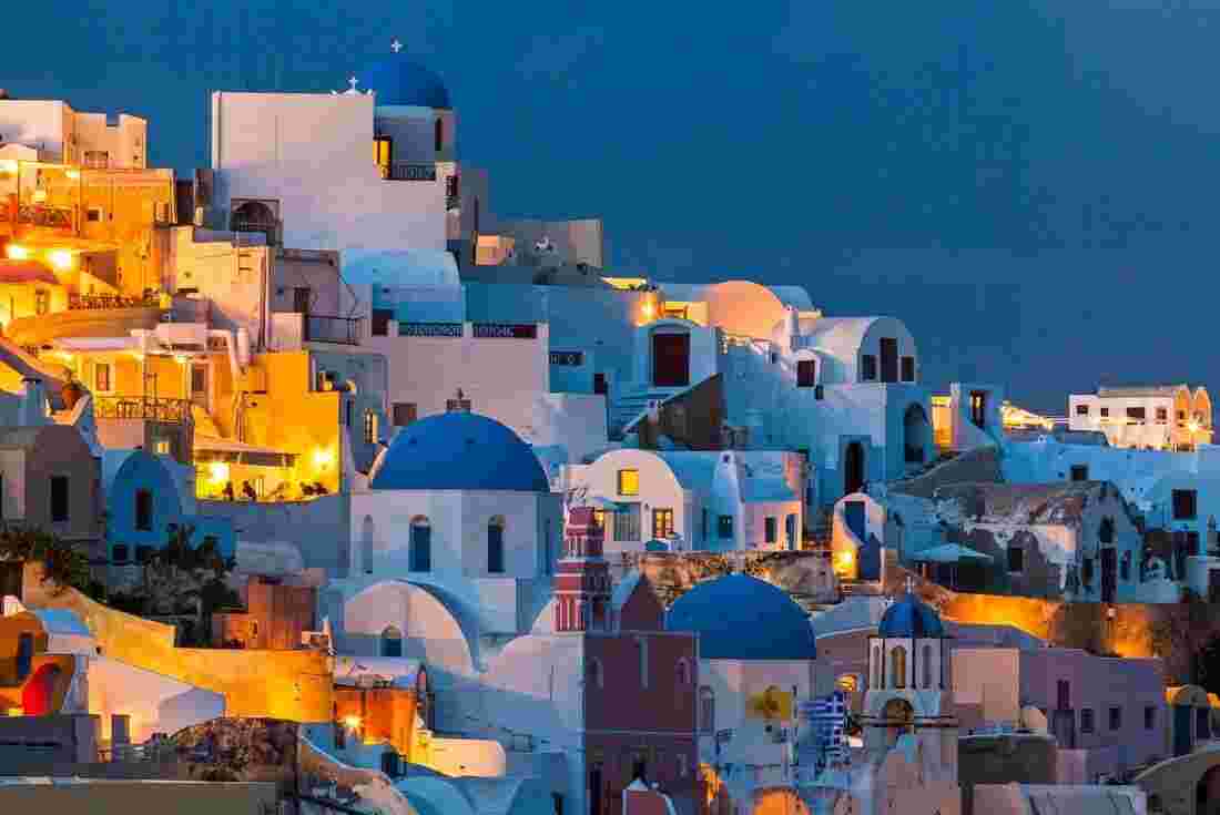 A nighttime view of Santorini's iconic white-washed houses and blue rooftops