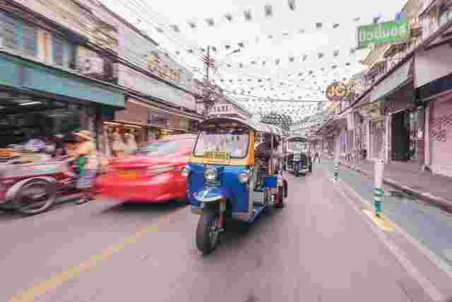 A tuk tuk driving down a road in Bangkok, Thailand