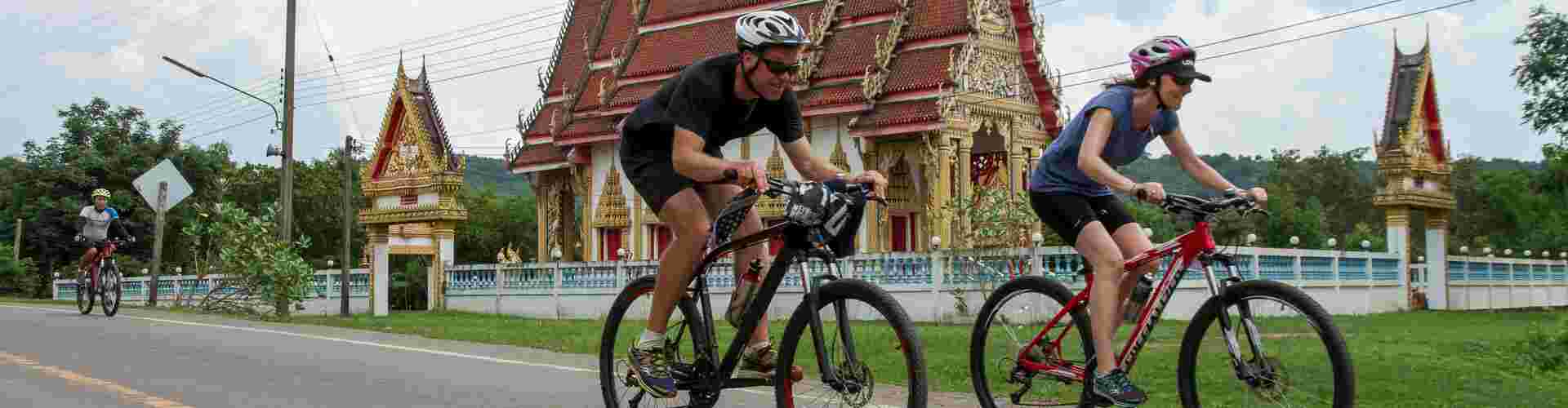 Intrepid cyclists riding past a temple in Thailand