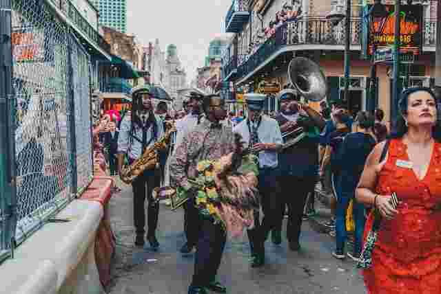 A boisterous second line parade marches down Bourbon Street in New Orleans