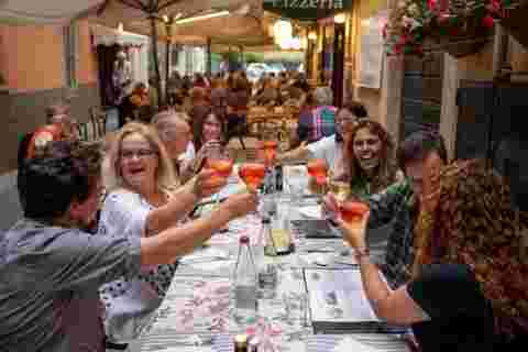 A group of travellers making a toast at dinner in Menaggio, Italy