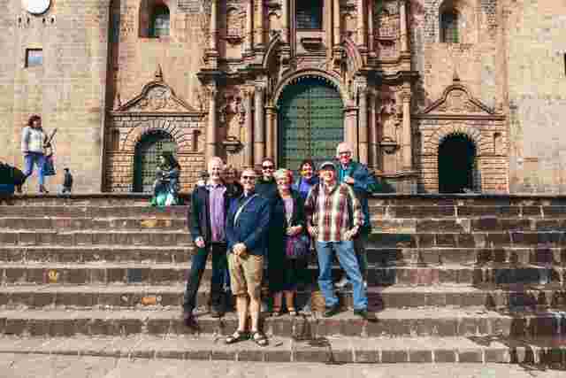 A group of people standing on the steps of a cathedral in Cusco, Peru