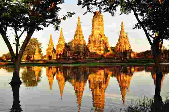 The history city of Ayutthaya reflecting on a lake at golden hour