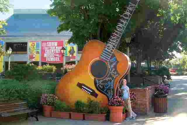 A woman poses with a giant guitar monument in Music City, USA