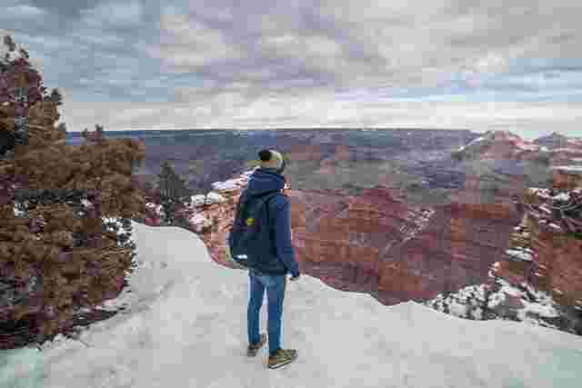A hiker admiring the views of a snow-dusted Grand Canyon in winter