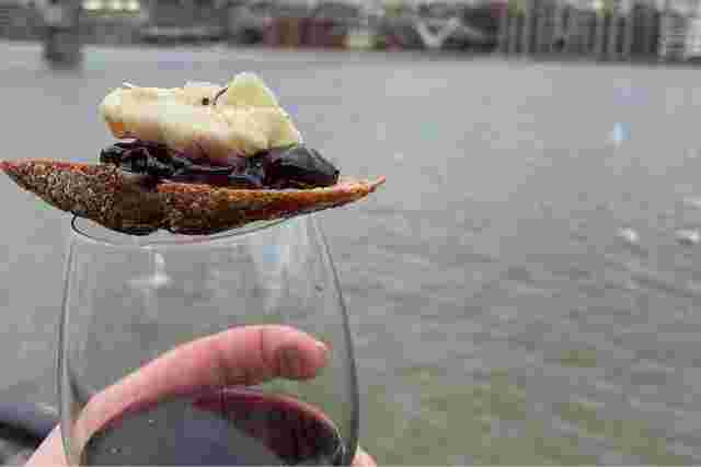 A glass of wine with Balkan cheese and a cracker balanced on top