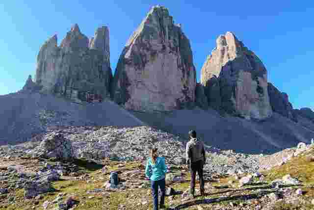 Two travellers walking toward the Tre Cime di Lavaredo in the Dolomites on a clear day