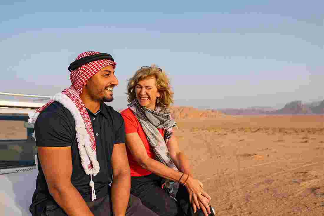 Traveller sits with leader on car bonnet in Wadi Rum desert