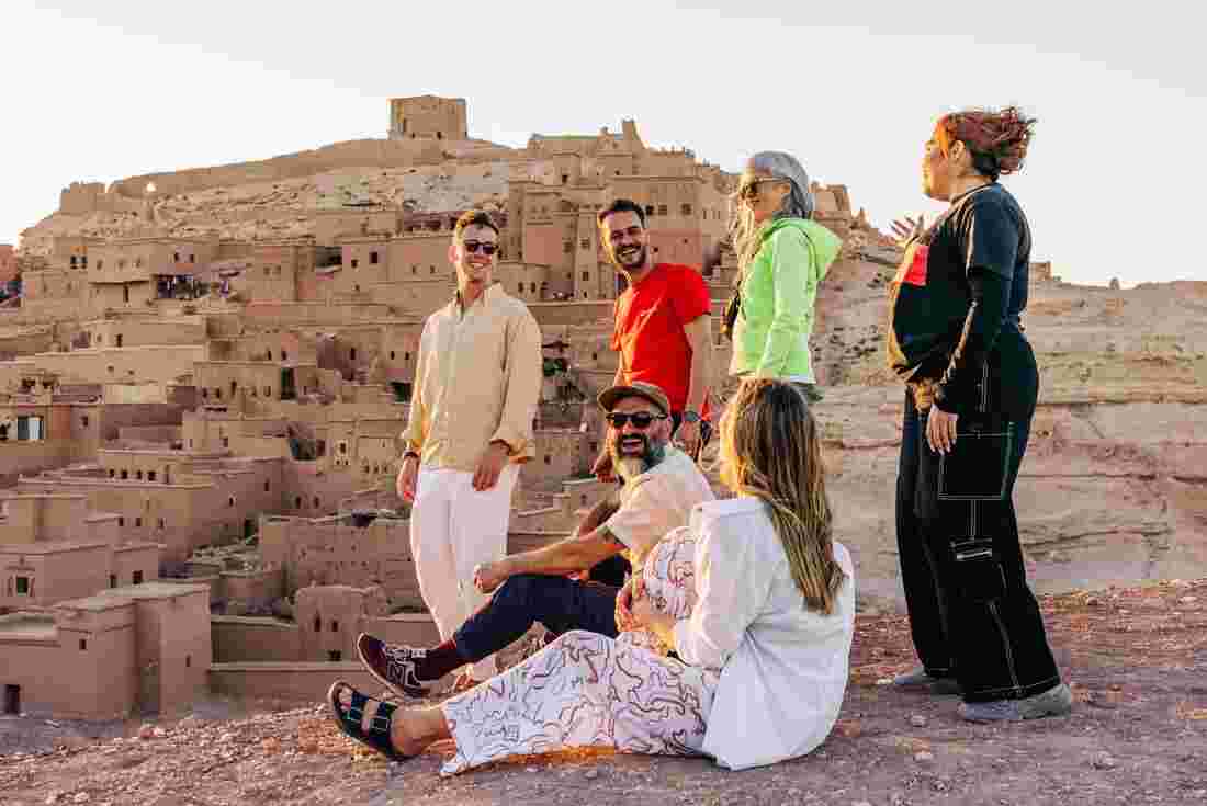 Group of travellers enjoying the sunset with their leader, Ait Benhaddou, Morocco