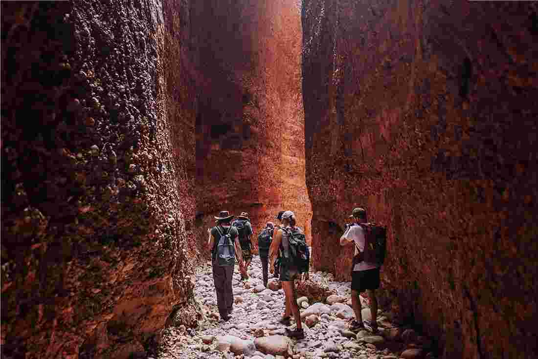 Group of Intrepid travellers walk through rock-strewn narrow passage