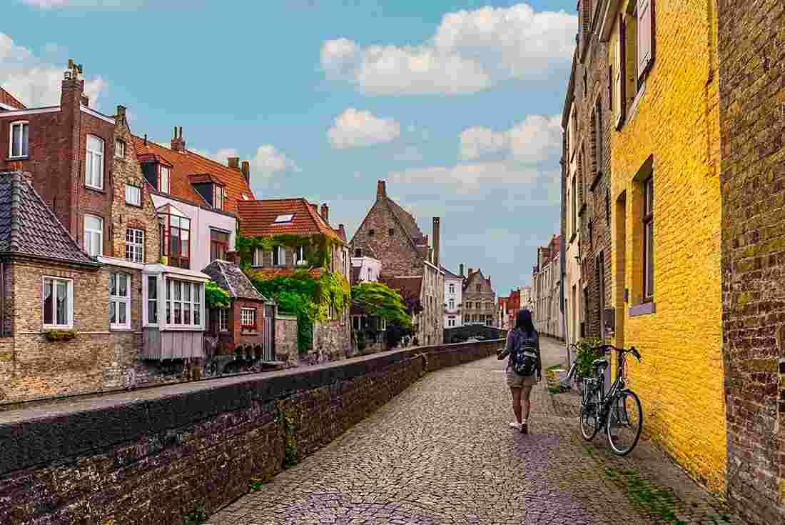 Traveller walks along Bruges canals 