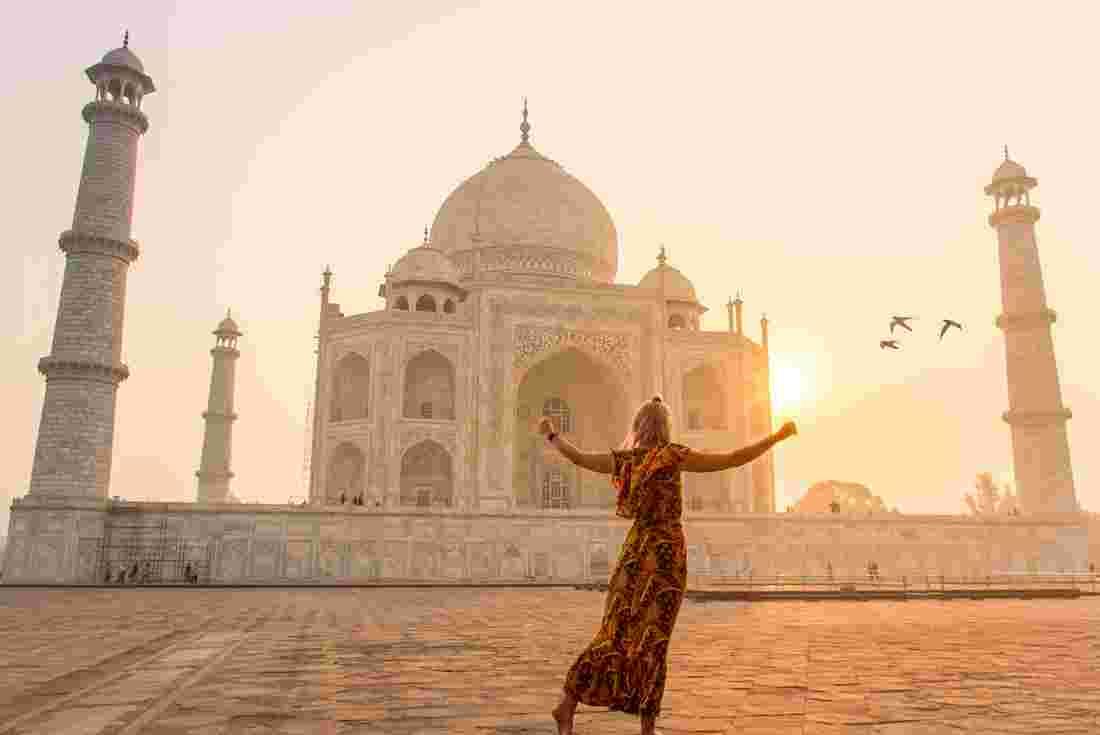 Traveller dancing in front of Taj Mahal at sunrise in India