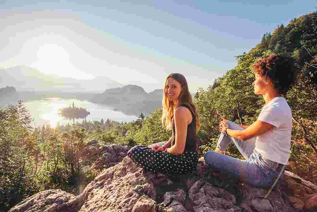 Two travellers sit on lookout over Lake Bled.