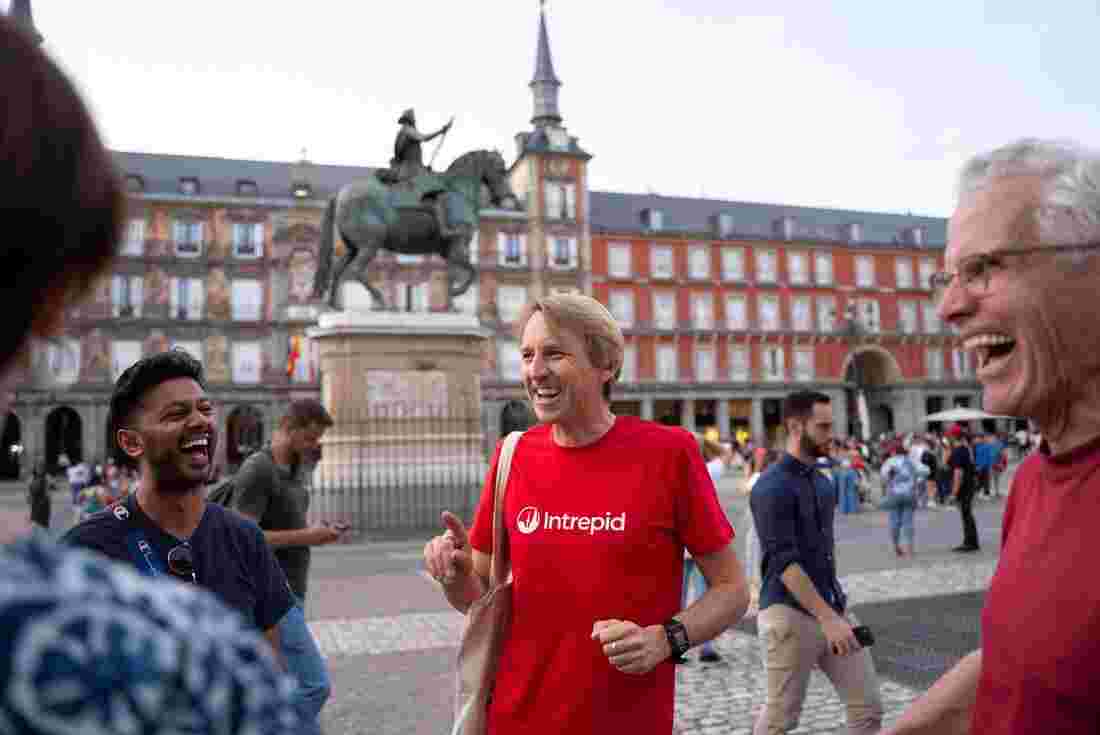 Group of travellers laugh as leader smiles in streeets of Madrid, Spain