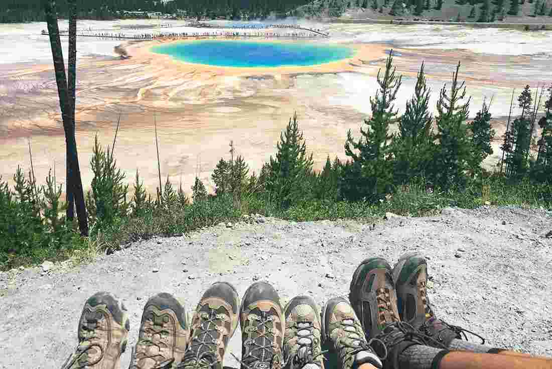 Hikers enjoying the views of the prismatic pools in Yellowstone NP, Wyoming, USA
