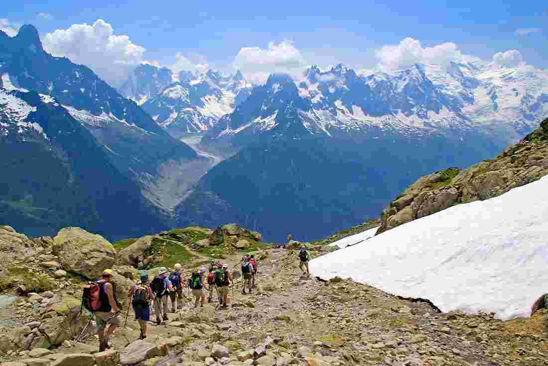 Group of hikers walking along bottom of Mont Blanc massif