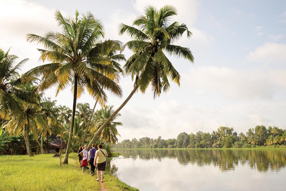 Tour group walking along the riverside of Kerala Backwaters, India