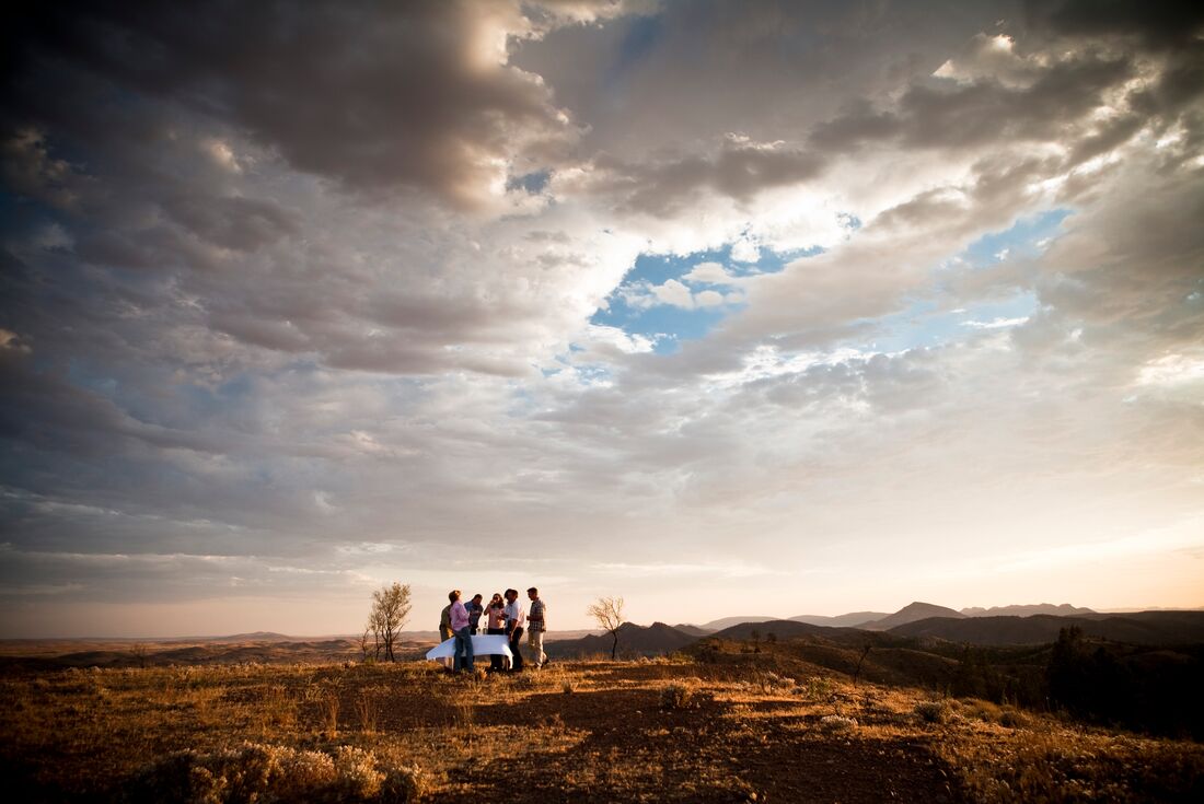 Wide view of travellers having a drink on a hilltop during sunset, Arkaba, South Australia