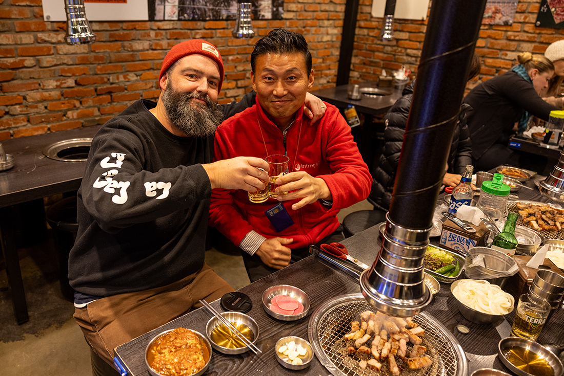 Smiling leader and traveller cheers beer at a group bbq dinner in Seoul, South Korea