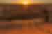 Group of travellers stand on a dune looking out at the sunset in Erg Chigaga