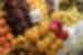 A close-up shot of dragon fruit in a pile at a market stall, surrounded by other fruit like grapes and kiwi fruit