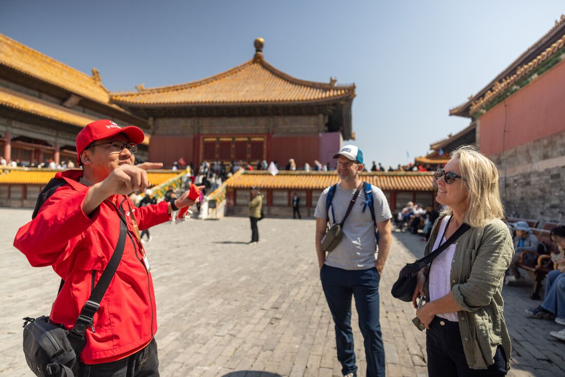 Leader talking to travellers while standing in the courtyard of the Forbidden City on a sunny day, Beijing, China