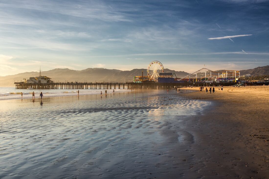 Santa Monica Pier at sunrise seen from LA Beach with Pacific Park behind in Los Angeles California USA