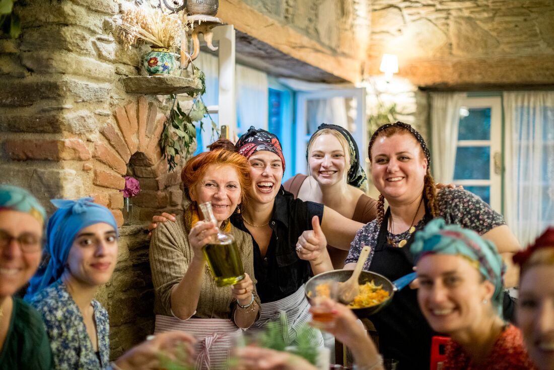 Travellers and hosts smile happily together during a cooking class