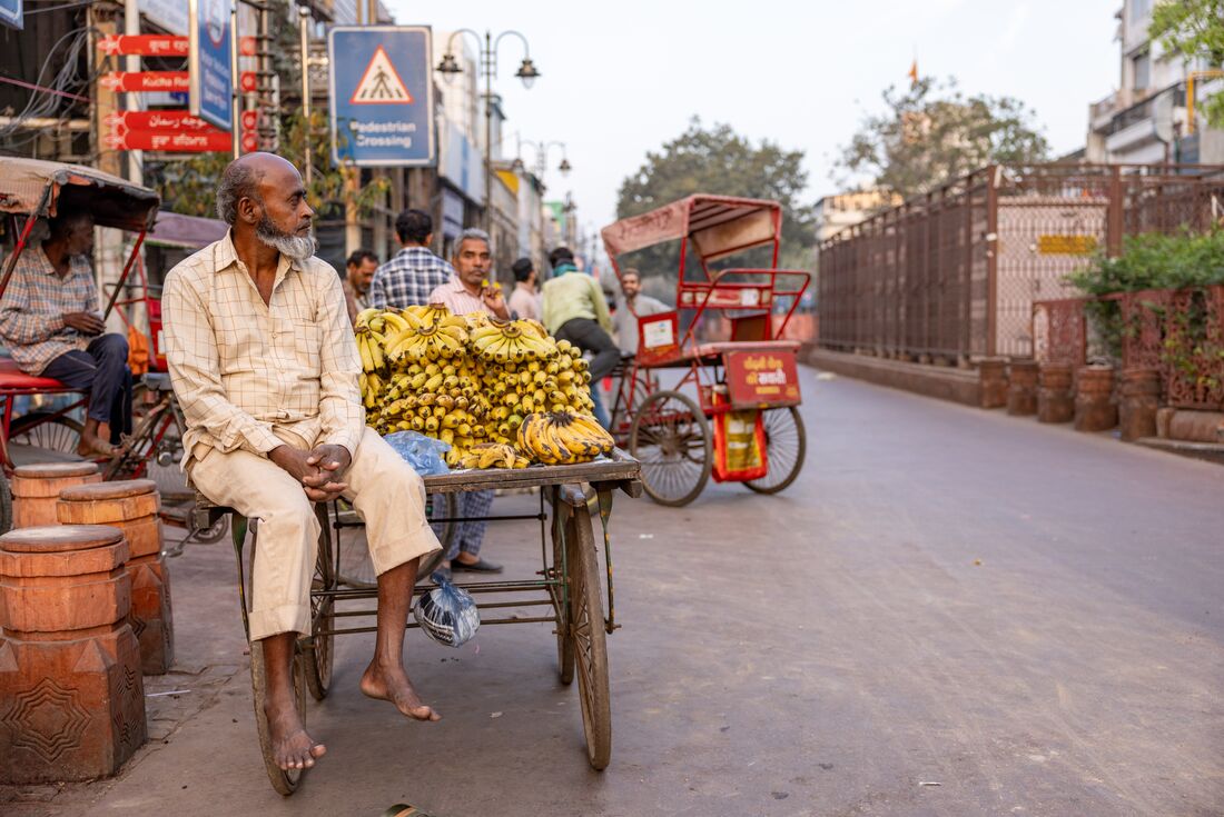 Local fruit vendor sitting on cart in Old Delhi, India